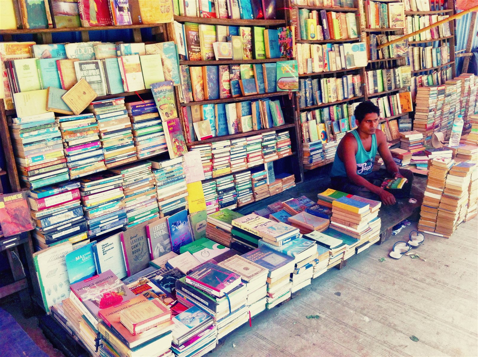 A street photo of a bookseller and shelves and rows of books stacked