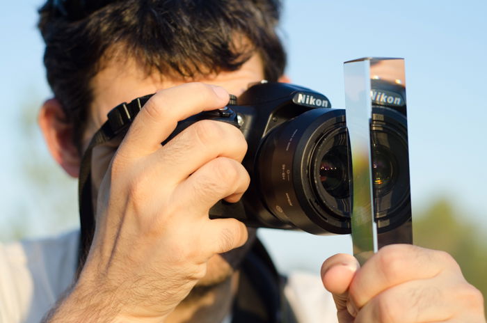 A photographer holding a photography prism in front of the lens of his canon DSLR 