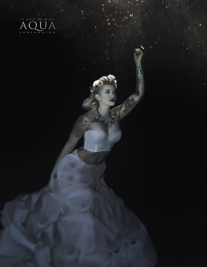 A stunning advertising photo of a woman with flowing white dress underwater