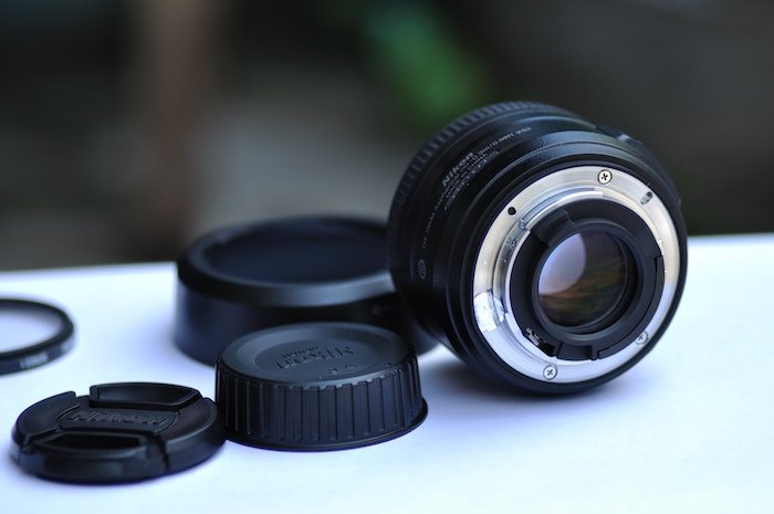 A camera lens resting on a white surface with different lens caps 