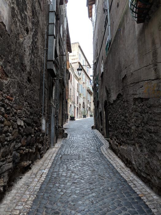 An architecture photo of cobblestones streets and brick buildings taken through an alleyway