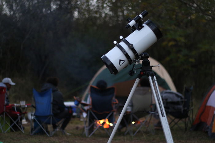 A telescope in the foreground of a campsite