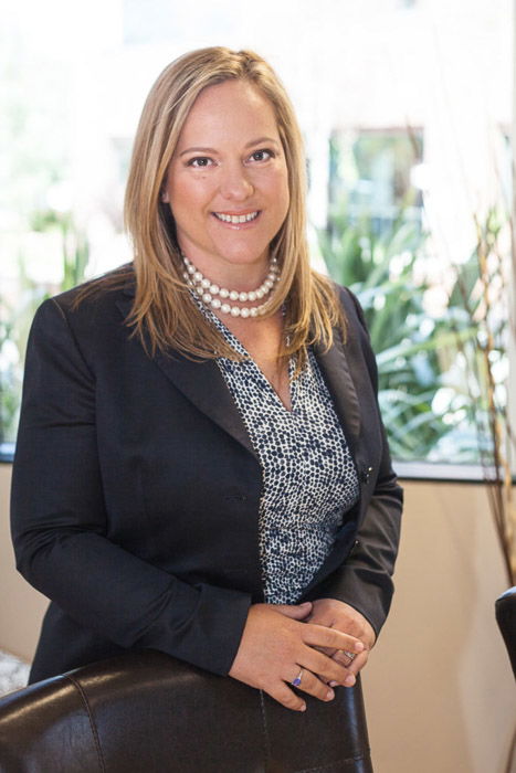 A corporate portrait of a woman in a business suit in an office setting