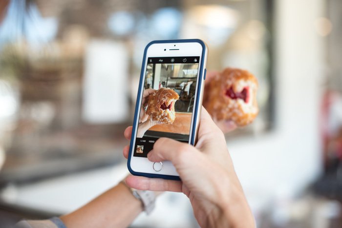 close up of a person taking an iPhone photo of food