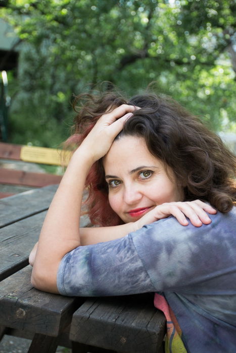 woman in grey leaning on wooden picnic table 3:2 photo