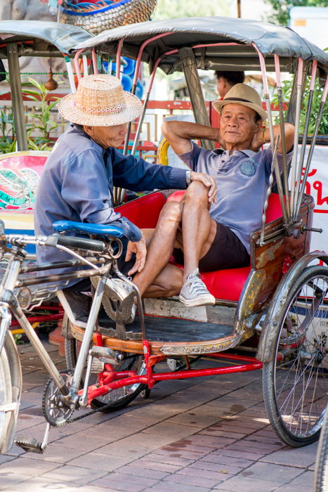 A documentary photography shot of two samlar drivers relaxing 