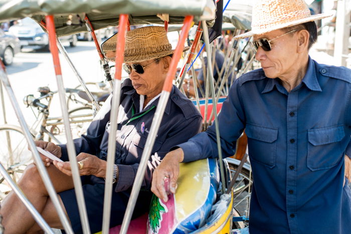 A documentary photography shot of two samlar drivers relaxing 