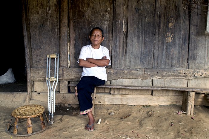 A Hmong man sitting outside his wooden house - editorial portrait photography tips
