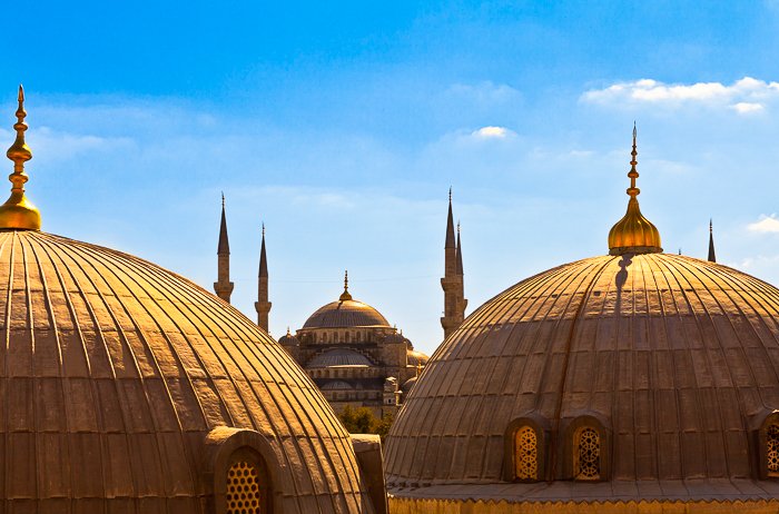 Golden domes of the Hagia Sophia, an ancient Byzantine structure, in Istanbul, Turkey, against a clear bright blue sky
