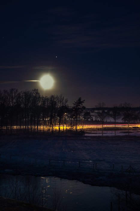 Light trails in a winter night under a full Moon (with Jupiter next to it).