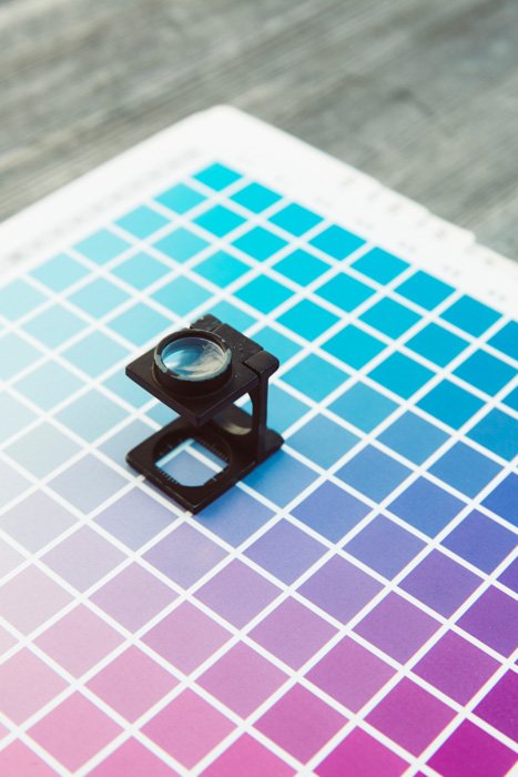 A magnifier resting on a grid of colors for photo printing paper