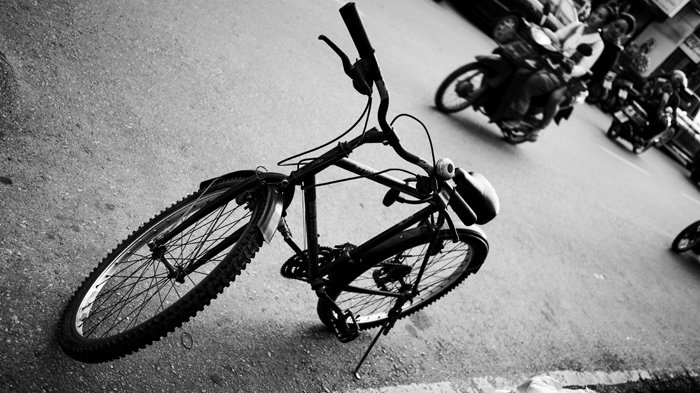 an angled black and white photo of a bicycle parked by the street