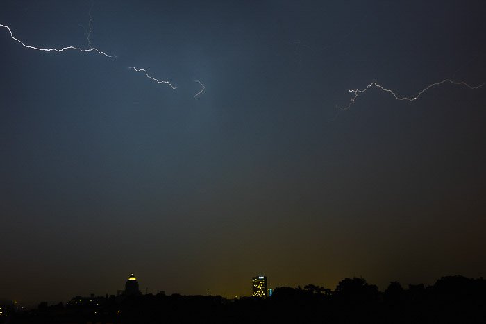 Atmospheric cityscape at night with lightning striking above