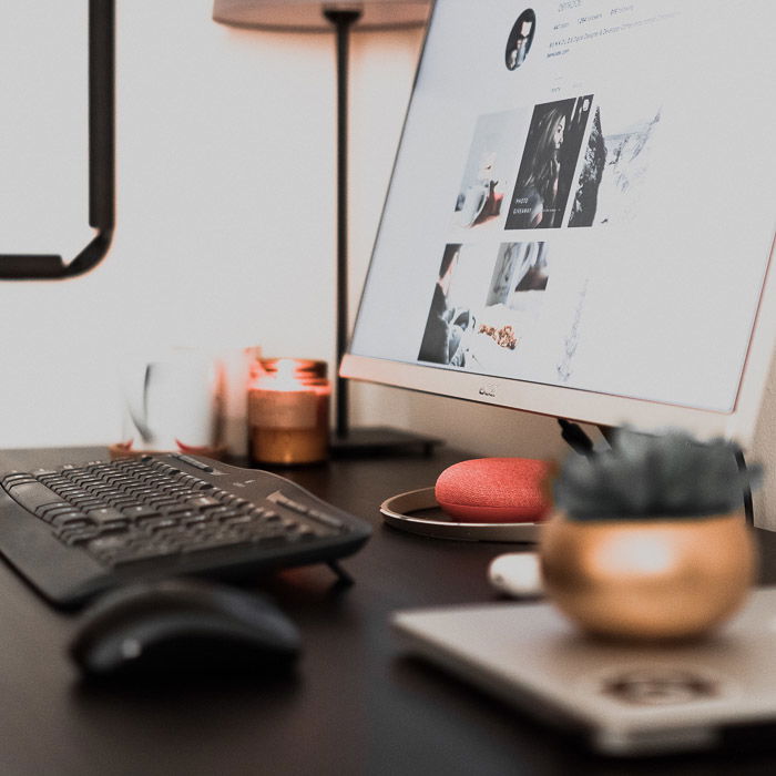 An office desk containing a computer, plant, lamp and other accessories