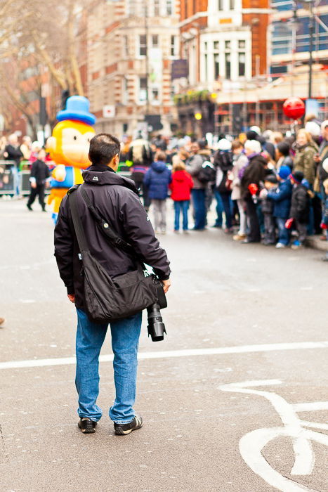 A man holding a DSLR watching the crowd at a carnival