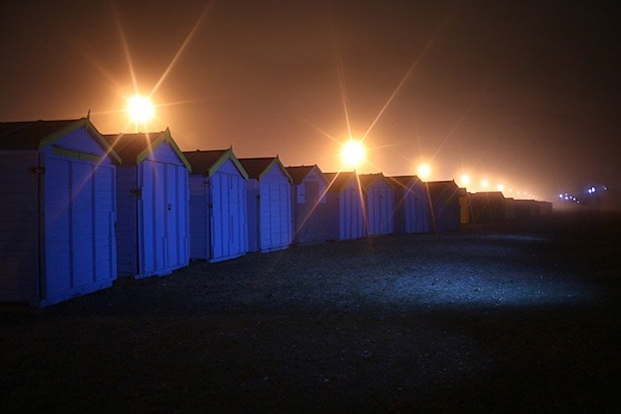 A night photography shot of a line of small wooden cabins