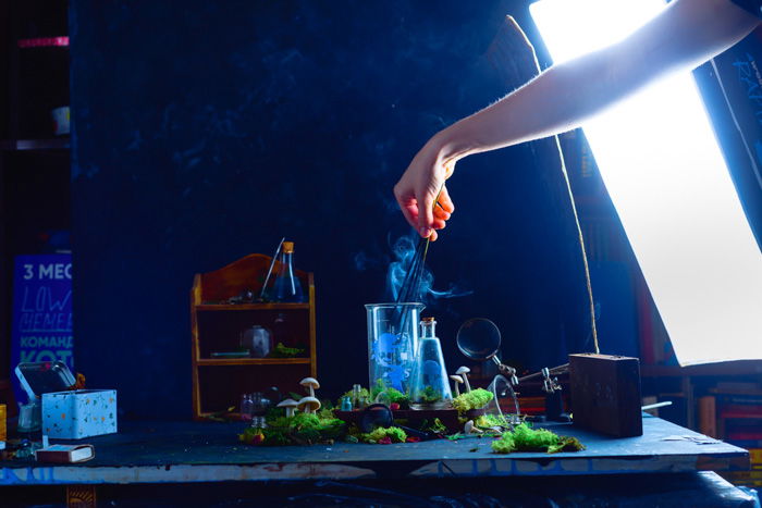 Setting up for a mystical still life featuring glass bottles with the silhouettes of tiny cutout characters inside and smoke billowing out