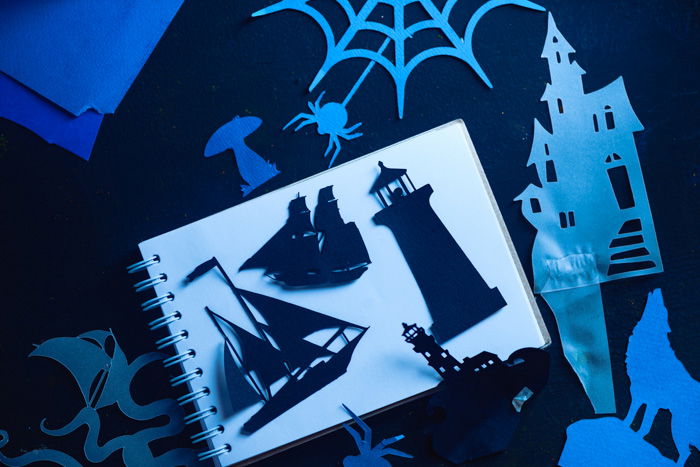 A variety of papercut silhouettes on a white notebook page 