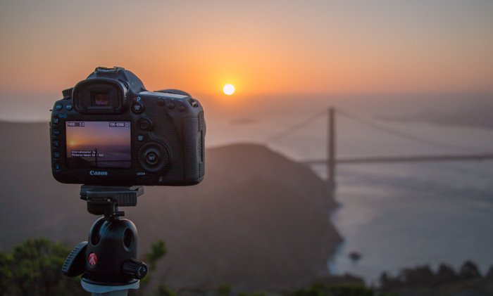 A DSLR camera set up on a Manfrotto tripod to capture a beautiful sunset