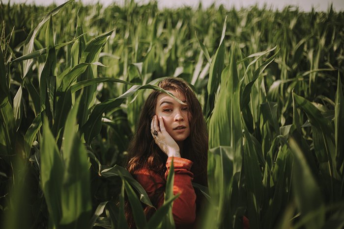 Portrait of a girl posing in long grass with cloudy day ambient light