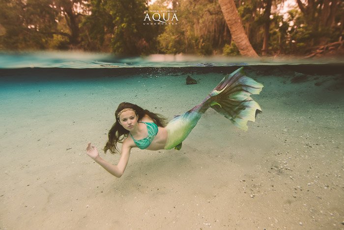 Stunning underwater photography shot of a young mermaid girl swimming underwater