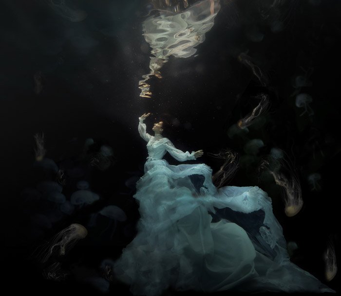dreamy photo of a woman with flowing white dress underwater