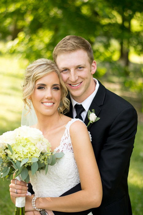 A portrait of the bride and groom embracing outdoors 