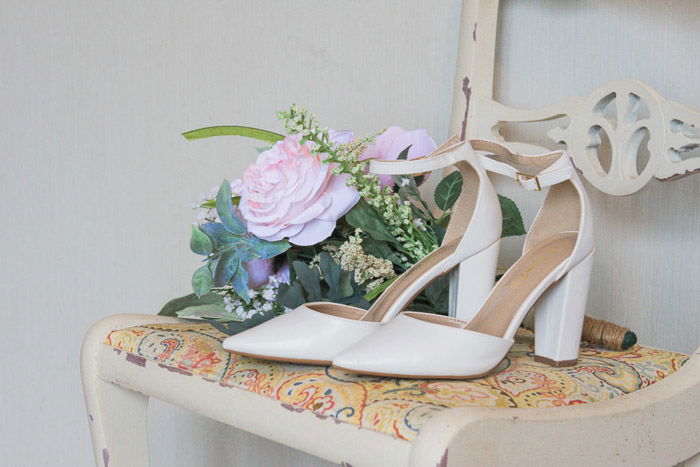 Still life of a pair of bridal shoes and a bouquet on a chair