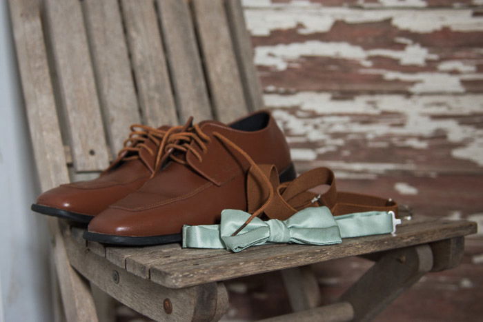 A shot of a pair of wedding shoes and a bowtie on a wooden chair