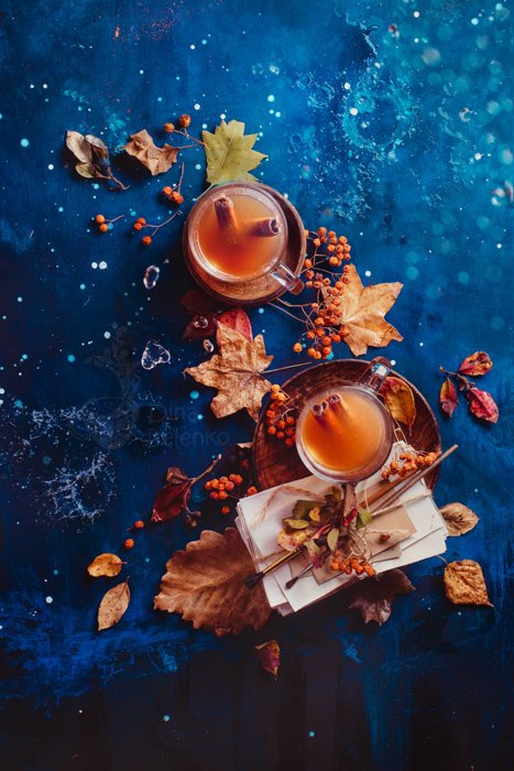 Autumn hot tea with ginger and cinnamon in a glass tea cup on a wet wooden background with copy space. Rainy autumn concept with fallen leaves and letters