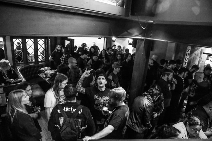 A black and white event photography shot of a crowd in the interior of a bar or concert venue