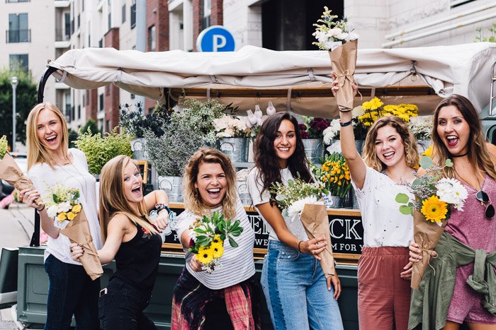 Fun group photo of girls holding bunches of flowers and smiling