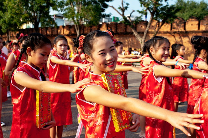 Asian girls wearing traditional red dresses line up for the Chinese new year parade in Chiang Mai, Thailand.