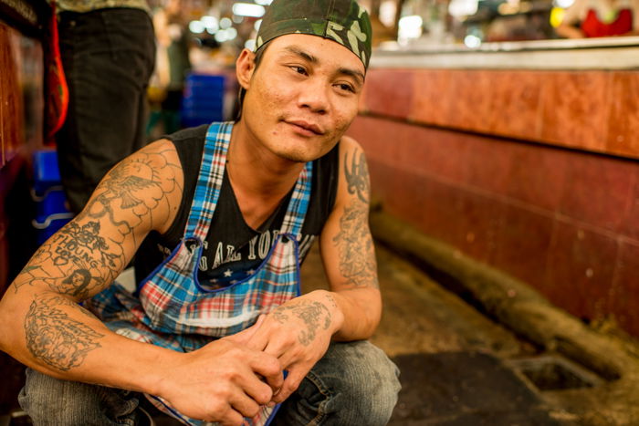 A street portrait of a Thai butcher kneeling on the ground - photography composition