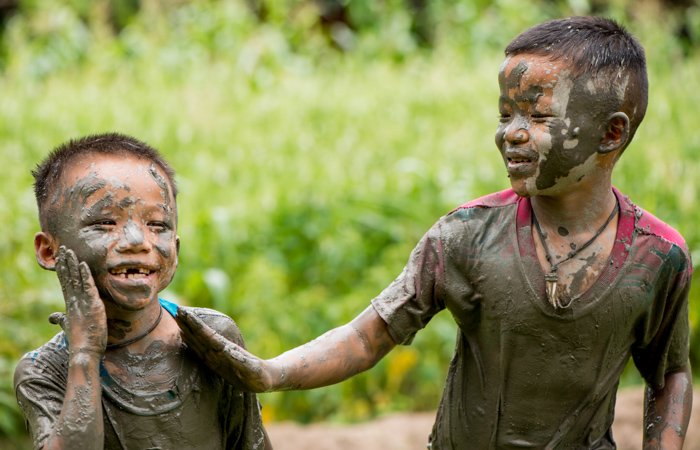 Two laughing Thai boys covered in mud - figure photography