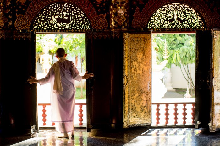 A porttrait of a Thai monk looking out a window - figure to ground photography