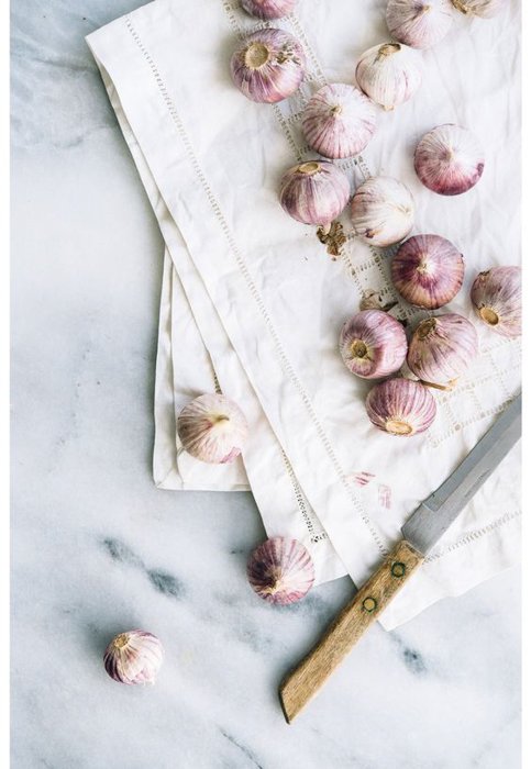 onions on a white sheet on a marble table next to a knife