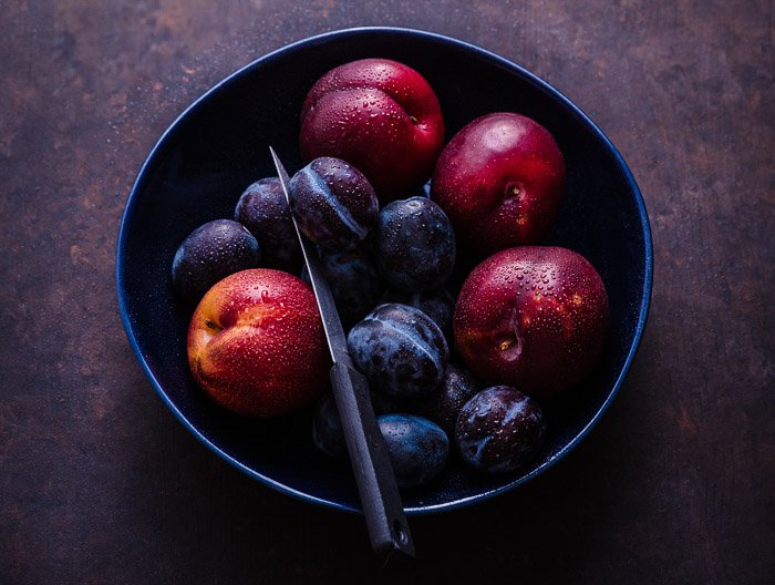 overhead food photo of a bowl of stone fruits