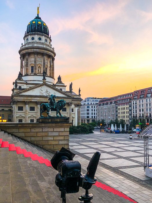 camera set up on a tripod at the steps at a square outside an old building with a blue dome, ready to take photos at sunset - stock photos that sell