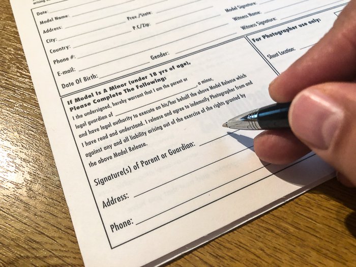 close up photo of a hand holding a pen near a form to sign - How to Take Stock Photos That Sell