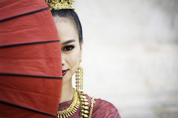 Interesting photography composition idea of a beautiful thai girl with half her face covered by an umbrella