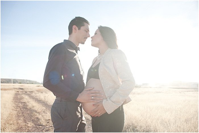 A romantic photo of pregnant couple outdoors, the bright sun behind them