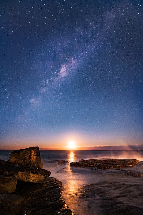 Stunny night photo of the moonrise and milky way by a coastal seascape