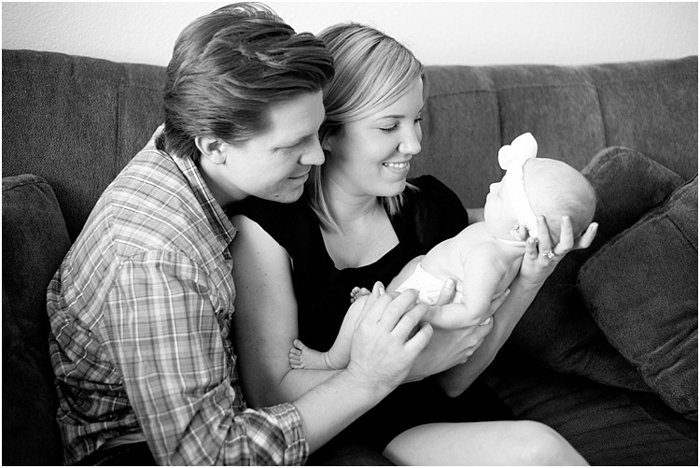 black and white photo of parent sitting on a sofa holding newborn