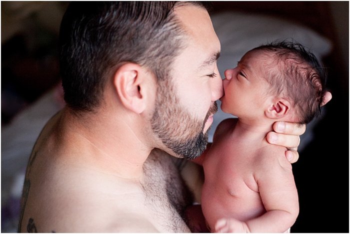 close up father nuzzling baby, baby biting father's nose during a newborn photo session