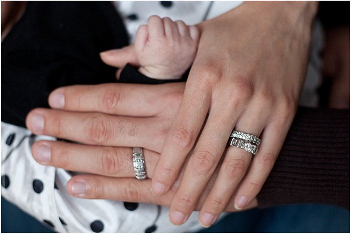 close up of parents' hands holding baby's arm, baby grasping dad's thumb