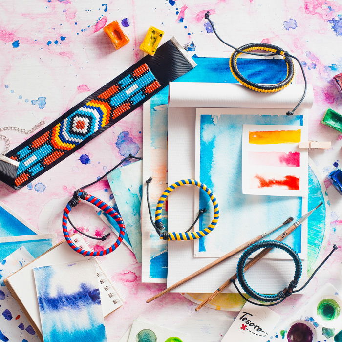 woven straps and bracelets on watercolor paintings on a pink and blue watercolor background