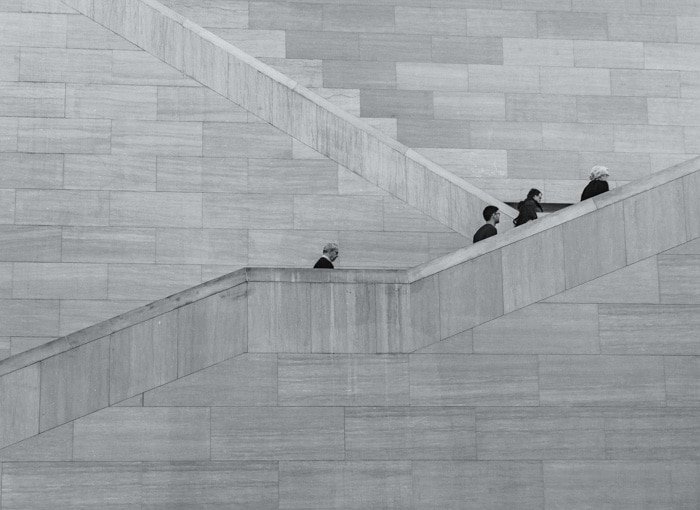 Black and white photo of four people climbing stone stairs 