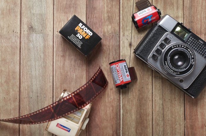flat lay of a film camera and rolls of film on a wooden background