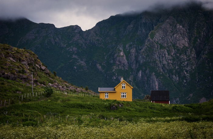 Two buildings surrounded by a beautiful mountainous landscape on a cloudy day